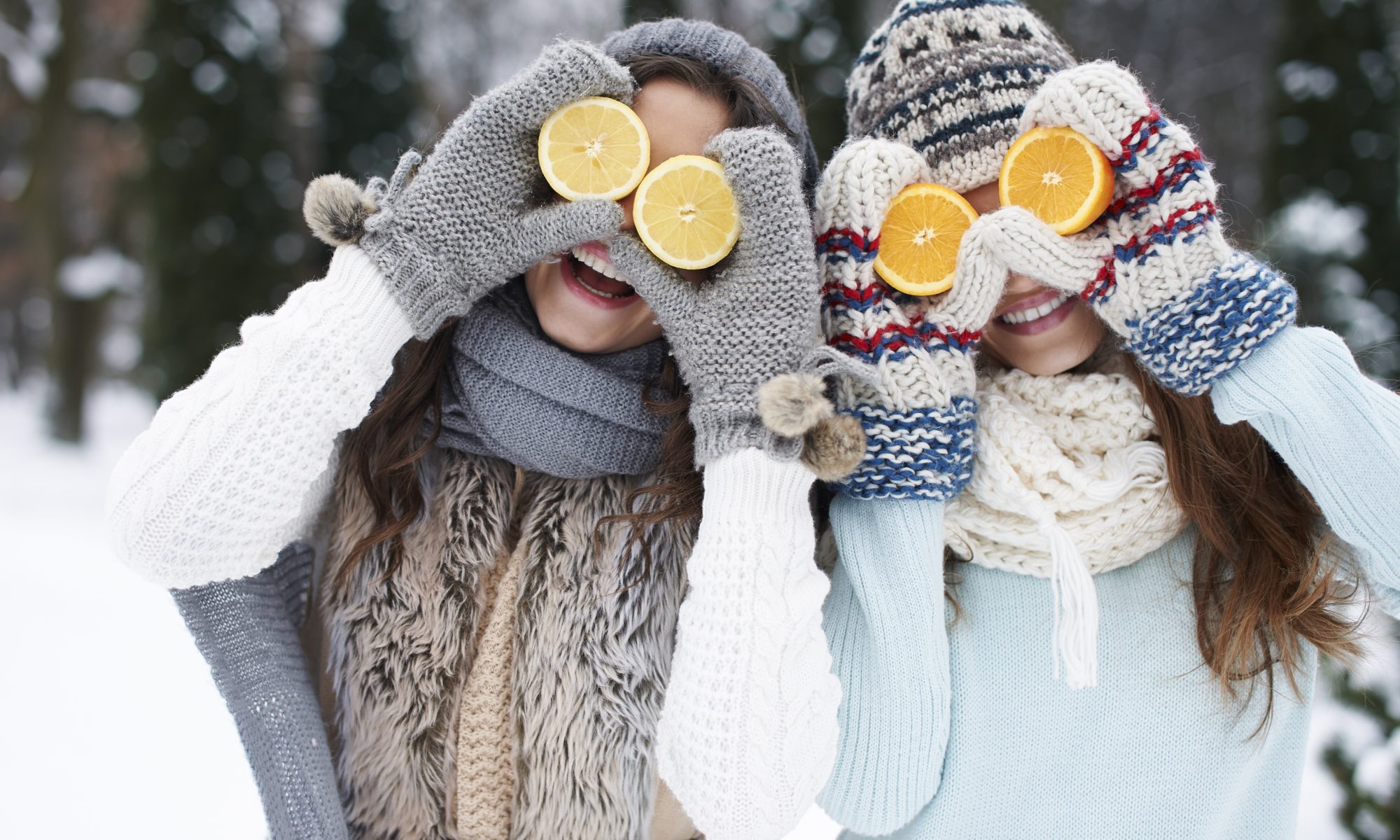 kobiety zimą z przyłożonymi do twarz połówkami cytrusów