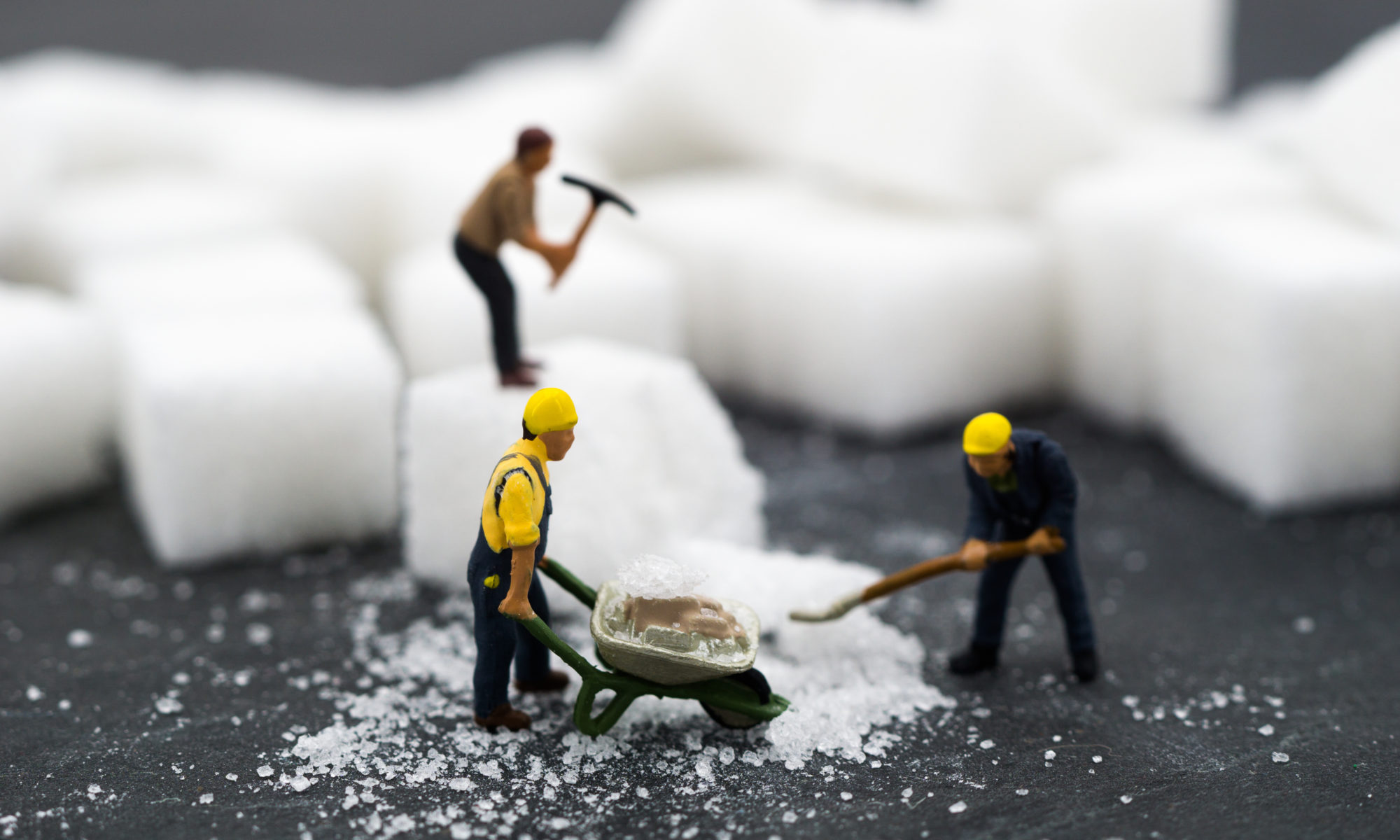 Miniaturowe figurki ludzików pracujących przy kostkach cukru